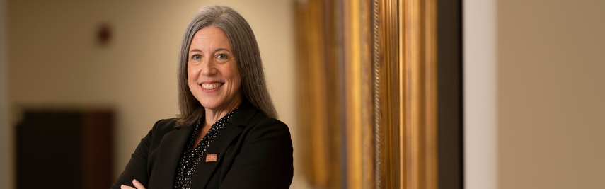 Woman smiling in front of gold picture frames.