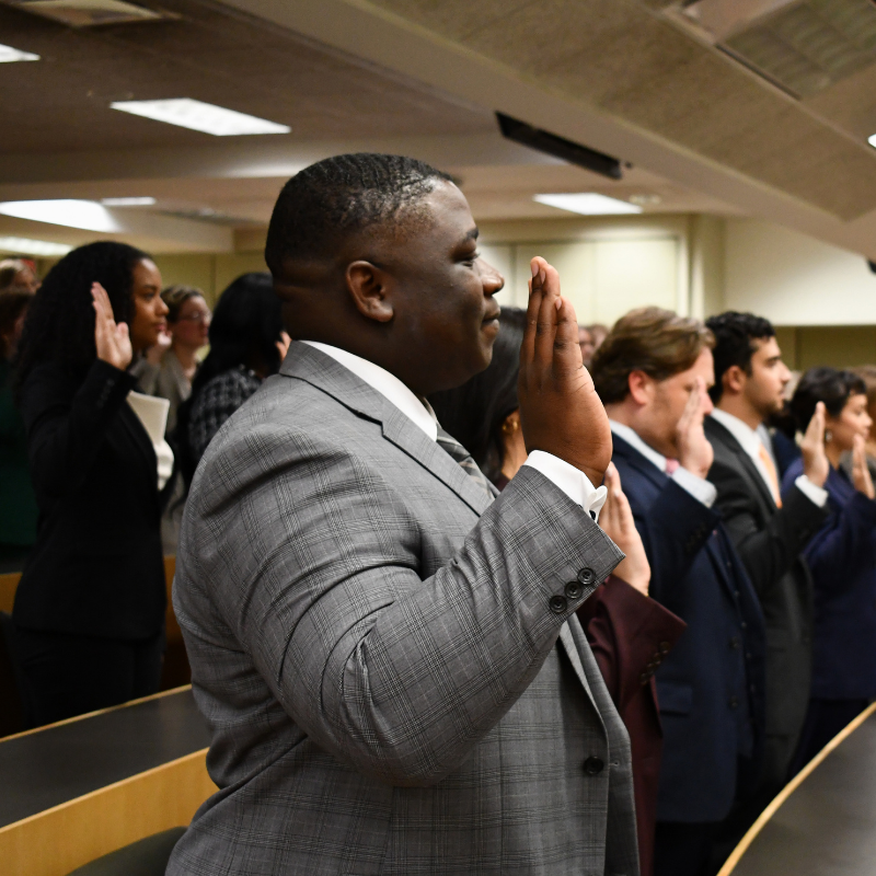 Student with hand raised to be sworn in as a student practitioner.