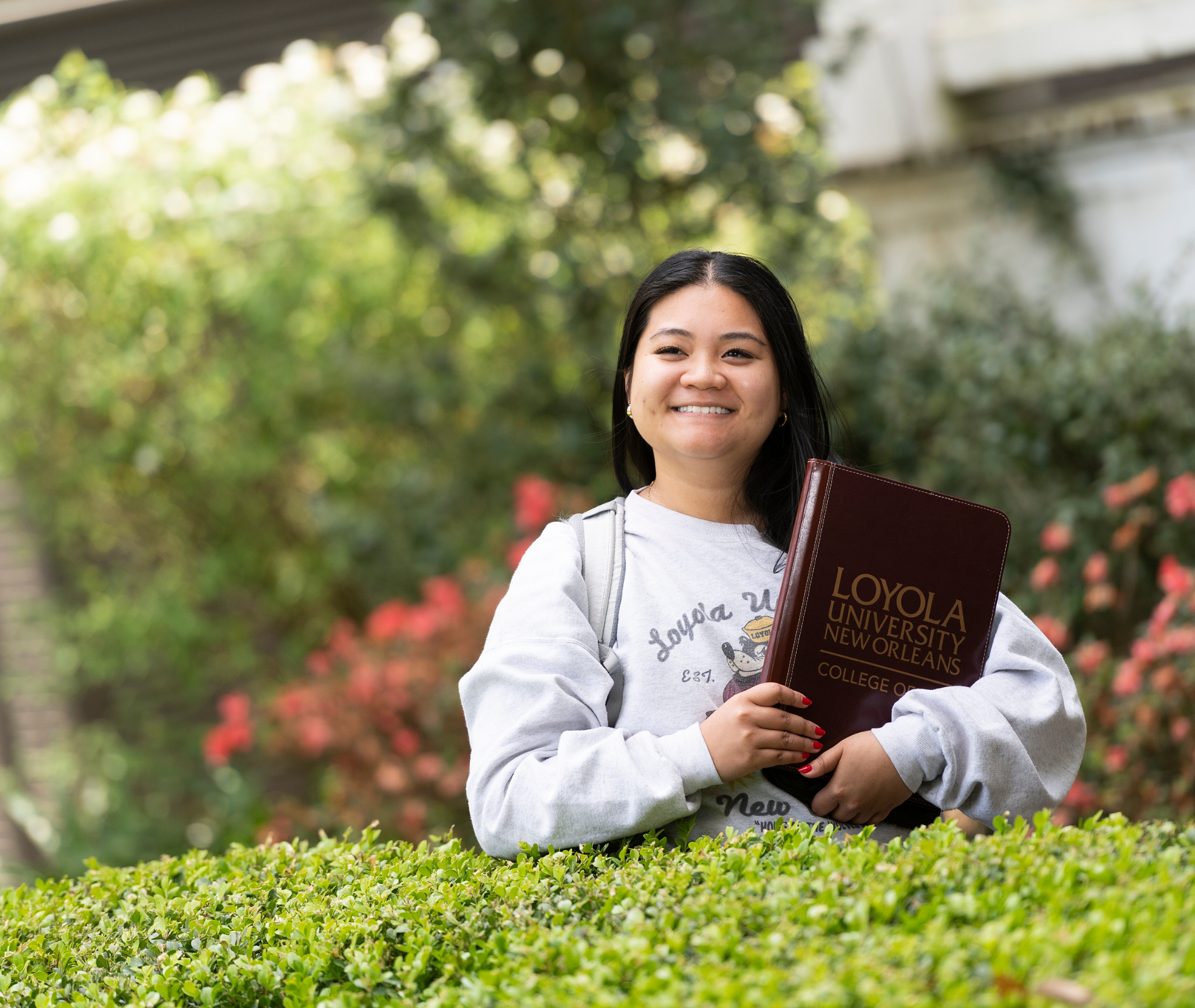 Student smiling with a Loyola University College of Law padfolio.