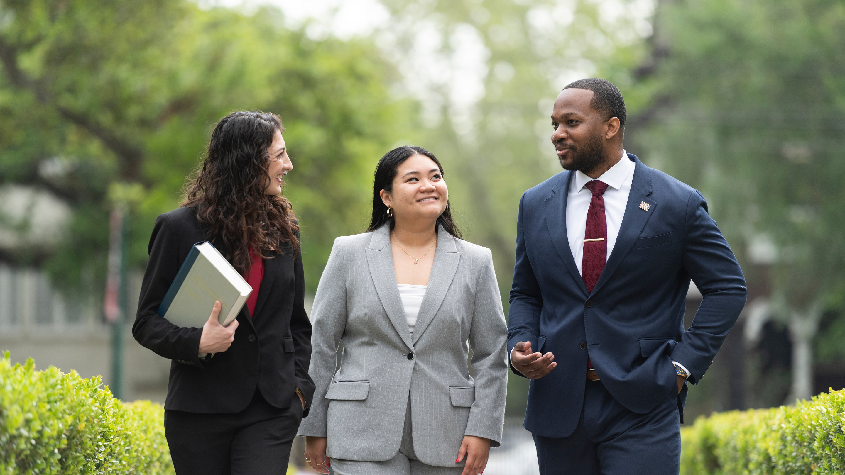 Three students in business attire talking.