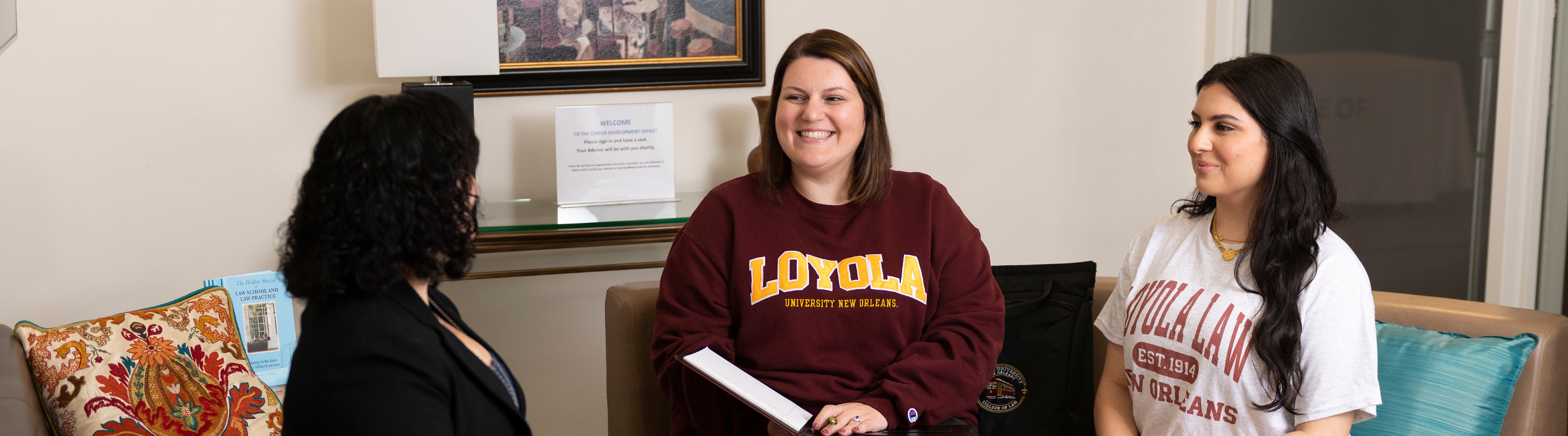 Two students in Loyola University New Orleans shirts sit with a career advisor.