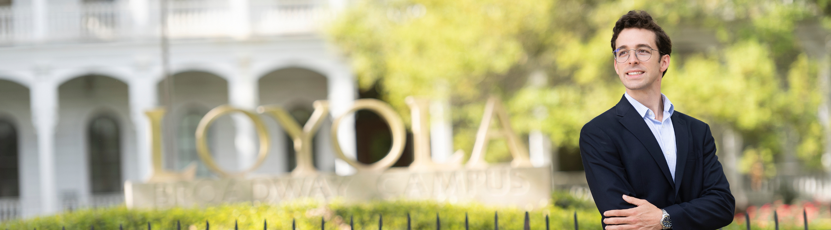 Smiling student standing in front of a Loyola sign.