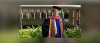 Jimmy Chilimigras poses in his graduation regalia in front of a streetcar at Loyola University New Orleans College of Law.
